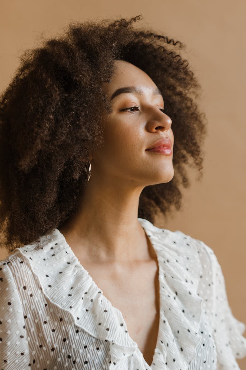 Portrait of a confident woman with afro hair wearing a polka dot blouse, exuding natural beauty and empowerment.