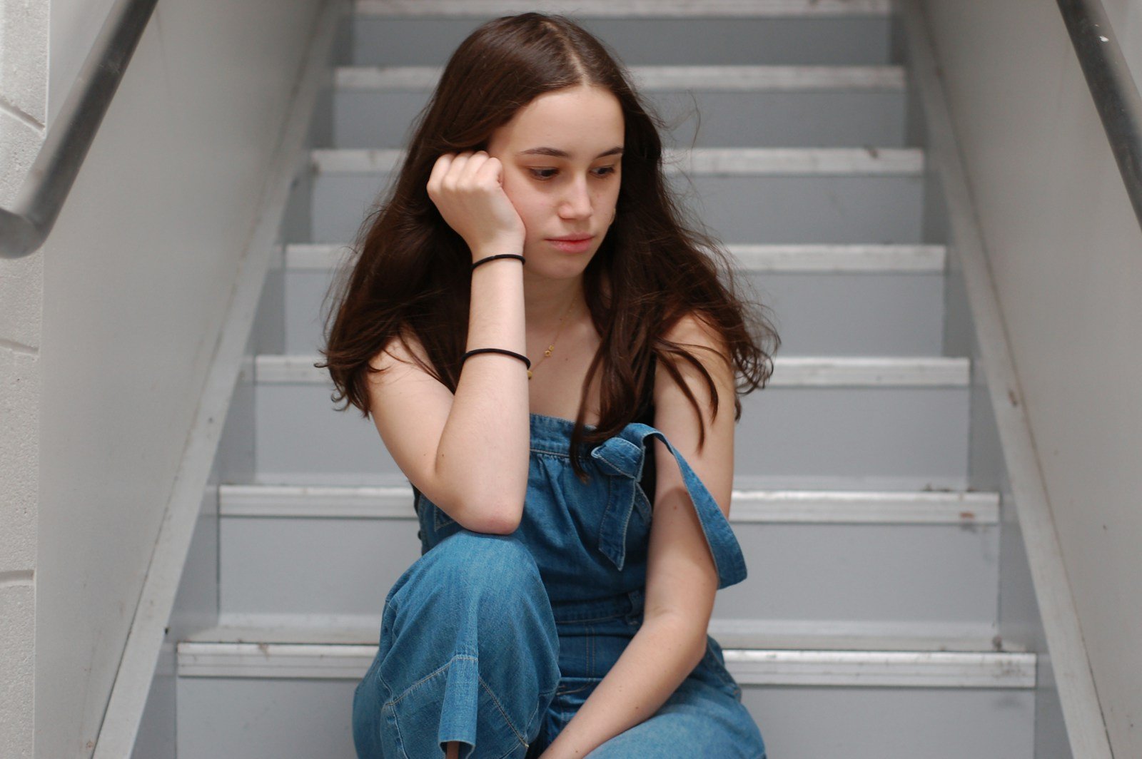woman in blue top sitting on stairs