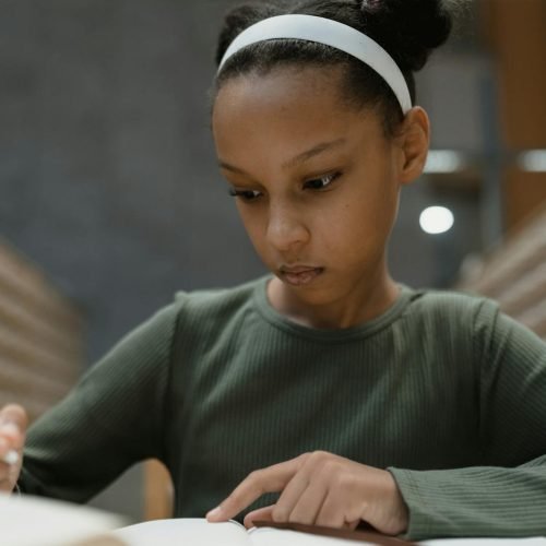 Young student writing attentively in a library. Ideal for educational themes.