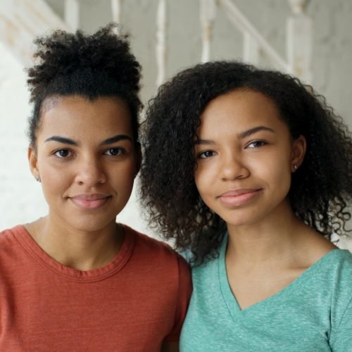 Two young women stand side by side.